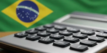 Calculadora mostrando valores financeiros com a bandeira do Brasil ao fundo, representando o cálculo do Auxílio Brasil.