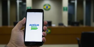 Pessoa usando smartphone para denunciar fraude no Auxílio Brasil
