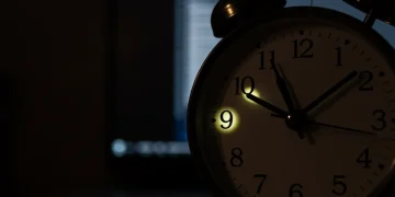 Relógio marcando horas noturnas e um computador, ilustrando o trabalho e o adicional noturno.